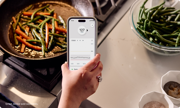 Gina checking her glucose levels while cooking - smart devices sold separately