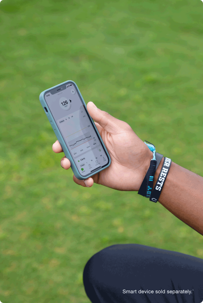 Hand holding phone showing glucose readings - smart device sold separately