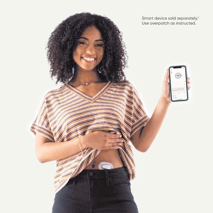 Woman holding smartphone with glucose levels, showing sensor on lower abdomen